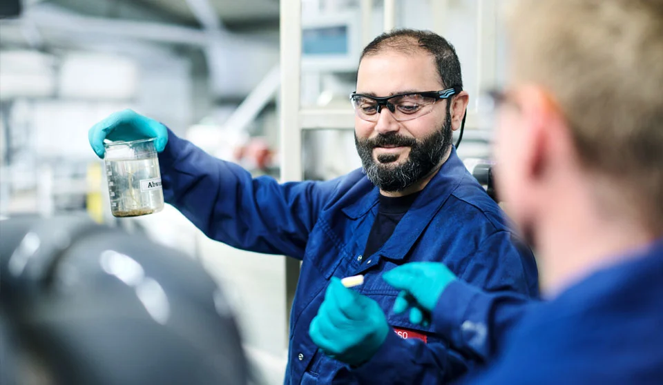 Un dipendente con occhiali protettivi tiene in mano un campione di liquido.
