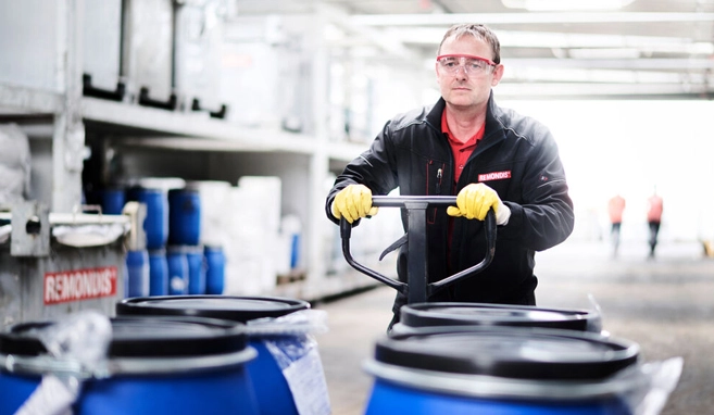 Un dipendente di REMONDIS Italia trasporta fusti con anelli elastici su un carrello elevatore nell'impianto di stoccaggio temporaneo dei rifiuti 