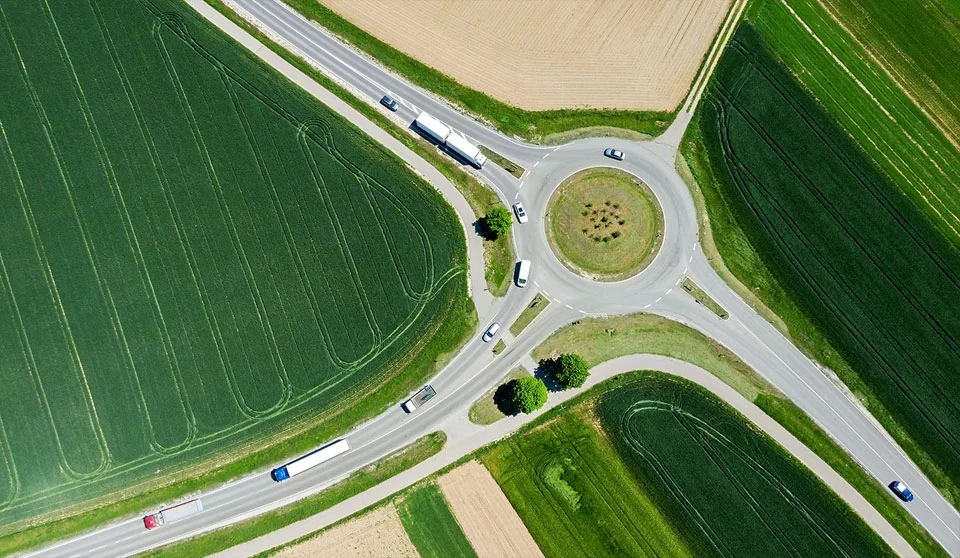 Veduta aerea di una rotatoria in un'area extraurbana con dei campi tutt'intorno.