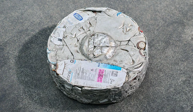 Blocco pressato metallico rotondo ricavato da bombolette spray usate e pressate.