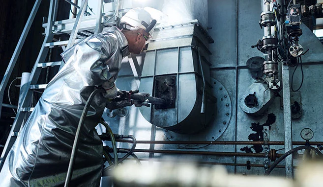 Dipendente con indumenti protettivi termici che lavora in un impianto di incenerimento ad alte temperature